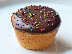 a cupcake with chocolate frosting and sprinkles on a white plate