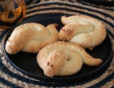 some biscuits on a black plate next to a glass of wine