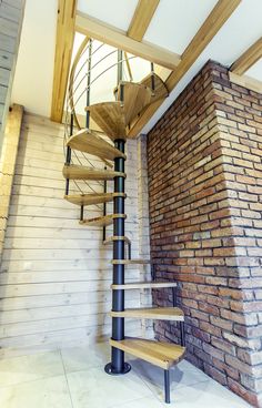 there is a spiral staircase in the corner of this room with brick wall and flooring