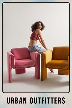 a woman sitting on top of a pink chair next to a yellow and orange chair