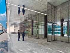 two men are standing in front of a building with glass walls and doors on both sides