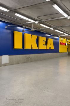 an empty parking garage with blue walls and yellow ikea signs on the side wall