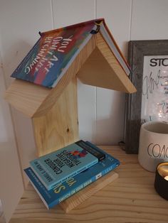 a wooden bird house sitting on top of a table next to a candle and some books