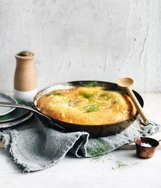 a skillet filled with food next to two wooden spoons on top of a table