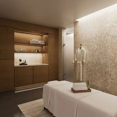 a spa room with two white towels on the bed and a bathrobe in the corner