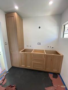 an unfinished kitchen with wooden cabinets and black flooring in the process of remodeling