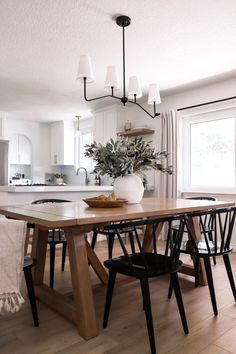 a dining room table with chairs and a potted plant on top of the table