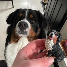 a hand holding a small dog figurine next to a person's hand