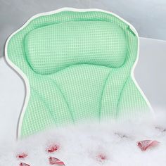 a green chair sitting in the middle of a pile of white foam with footprints on it