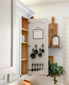 a kitchen with white cabinets and black utensils hanging on the wall above it