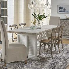 a dining room table with chairs and a rug on the floor in front of it