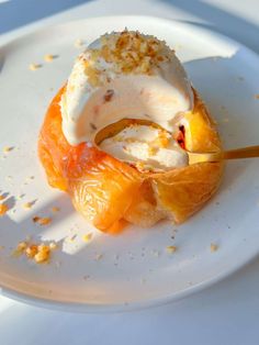 a white plate topped with an orange covered in ice cream