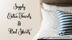 a bed with white sheets and blue striped pillows on it, next to a wall sticker that says supply extra towels & bed sheets