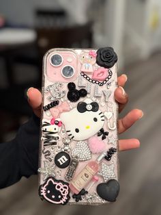 a person holding up a phone case with hello kitty on the front and other items attached to it