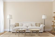 a living room with a white couch and two tables in front of a book shelf