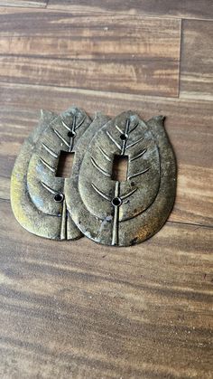 two pieces of metal sitting on top of a wooden floor next to each other with holes in the middle