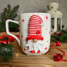 a coffee cup with a santa claus face on it and christmas decorations around the mug