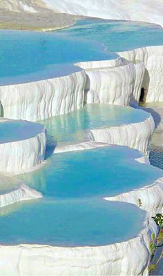 several blue pools are in the middle of a desert area with white rocks and green plants