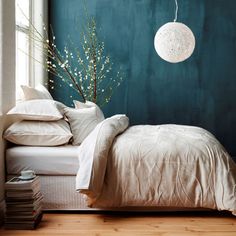 a bedroom with teal walls, white bedding and pillows on the bottom floor