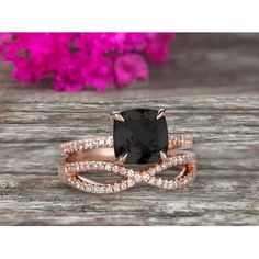 an engagement ring set with a black diamond and two white diamonds on the band, in rose gold