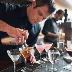 a man pouring drinks into glasses at a bar