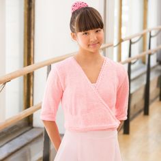 a young woman standing in front of a wooden railing with her hands on her hips