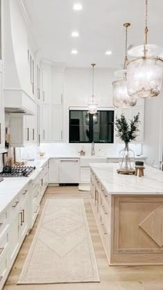 a large kitchen with white cabinets and marble counter tops