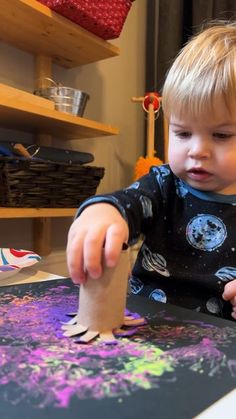 a little boy that is playing with some kind of paint on the paper and glue