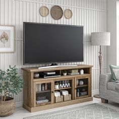 a flat screen tv sitting on top of a wooden entertainment center in a living room