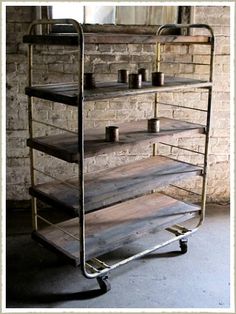 a metal shelf with candles on it in front of a brick wall