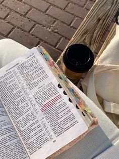 an open bible sitting on top of a table next to a cup of coffee