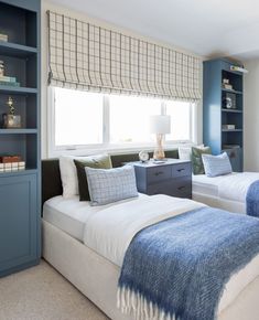 two twin beds in a bedroom with blue and white decor on the walls, along with bookshelves