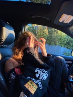 a woman sitting in the back seat of a car with her hand on her head