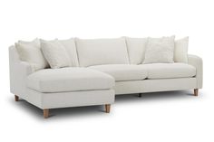 a white sectional couch with pillows on it's back and side facing each other