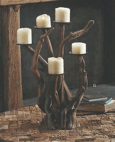 a candle holder made out of branches with candles in it on a table next to a book