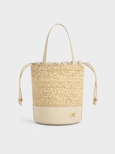 The quintessential bucket bag with a summer-friendly twist. This piece features a classic cylindrical shape, with a leather bottom offering a smooth contrast to the intricate woven finish and providing extra stability. It also includes a drawstring closure for quick and easy access to your belongings while keeping them safe and secure. The emblem adds a subtle touch of glamour in gold, further elevating this sophisticated design. Cheap Summer Cream Bucket Bag, Cheap Gold Bucket Bag, Luxury Straw Bucket Bag With Woven Leather, Luxury Woven Leather Straw Bucket Bag, Chic Leather Bucket Bag With Basket Shape, Chic Leather Basket-shaped Bucket Bag, Chic Leather Bucket Bag In Basket Shape, Chic Leather Basket Bucket Bag, Luxury Leather Basket Bucket Bag