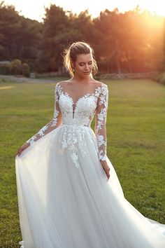 a woman in a wedding dress standing on the grass