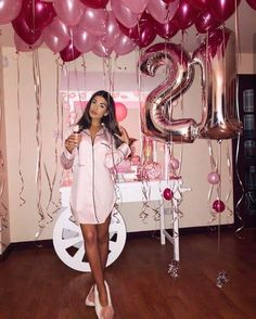 a woman is standing in front of balloons and the number twenty two, with her hands on her hips