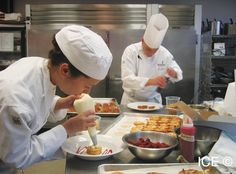 two chefs preparing food in a commercial kitchen