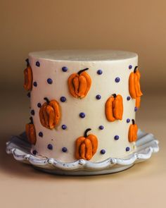 a white cake decorated with orange pumpkins and blue polka dots on a platter