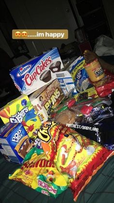 a pile of snacks sitting on top of a bed next to a bag of chips