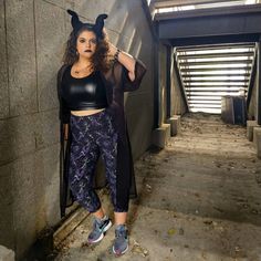 a woman standing next to a wall with her hands in her hair and wearing devil ears