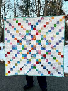 a person holding up a quilt made with squares