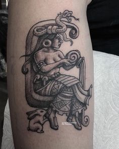 a black and white tattoo on the leg of a person with a snake around his neck