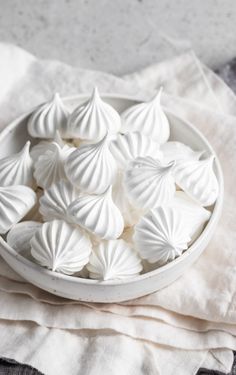 a white bowl filled with sea shells sitting on top of a table next to a napkin