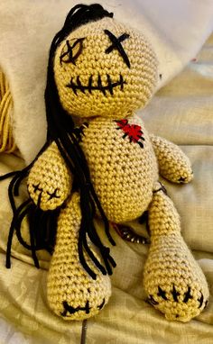 a crocheted doll with long hair laying on a bed