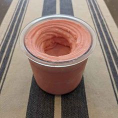 a plastic cup filled with pink liquid on top of a striped table cloth