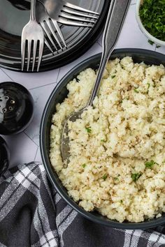 a bowl filled with rice next to two forks