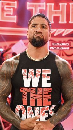 the rock wearing a we the ones t - shirt in front of a stage backdrop