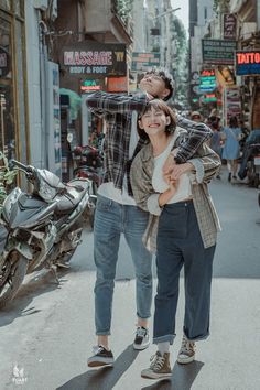 a man and woman walking down the street in front of some stores with motorcycles behind them